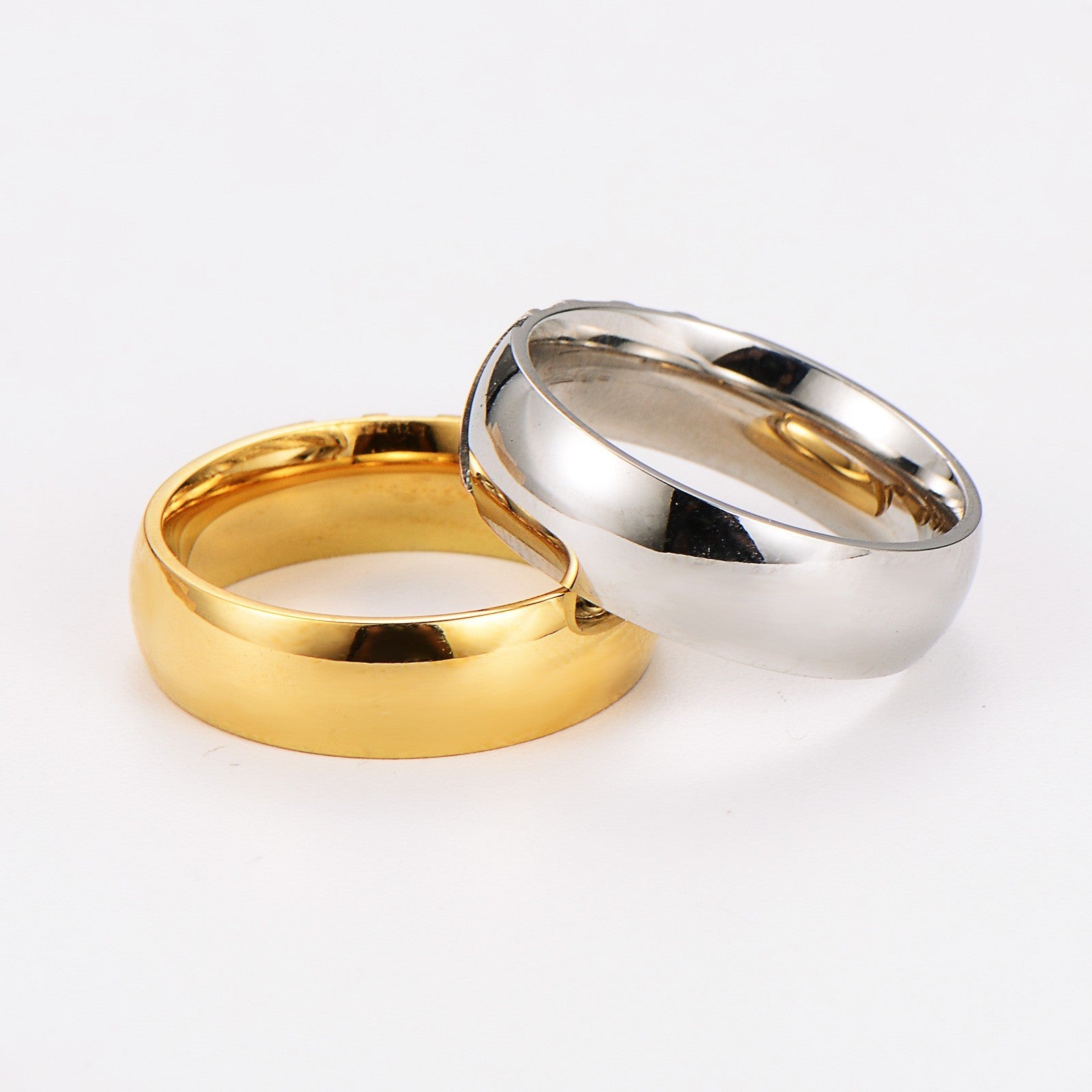 Zwei schlichte Ringe, einer goldfarben, einer silberfarben, auf weißem Hintergrund.