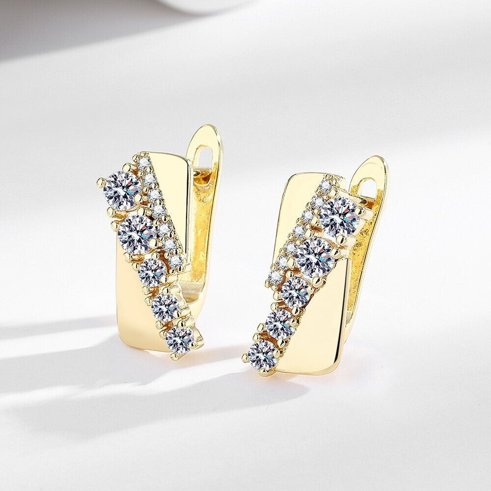 Elegante goldene Ohrringe mit glitzernden Zirkonia-Steinen auf weißem Hintergrund