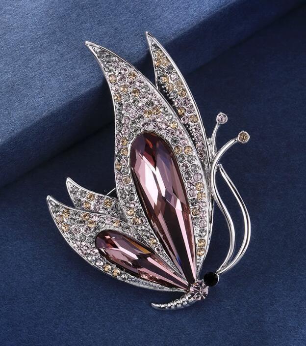Schmetterling Brosche mit lila und klaren Strasssteinen auf blauem Hintergrund, eleganter Damenschmuck