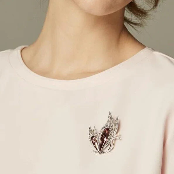 Elegante Damenbrosche in Silber mit funkelnden Steinen an rosa Oberteil, stilvoller Schmuck