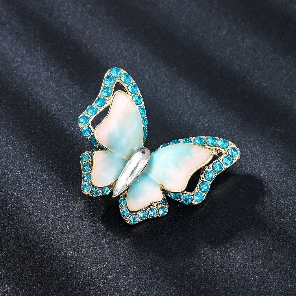 Schmetterling Brosche mit blauen Kristallen und Perlmuttflügeln auf schwarzem Hintergrund