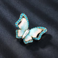 Schmetterling Brosche mit blauen Kristallen und Perlmuttflügeln auf schwarzem Hintergrund